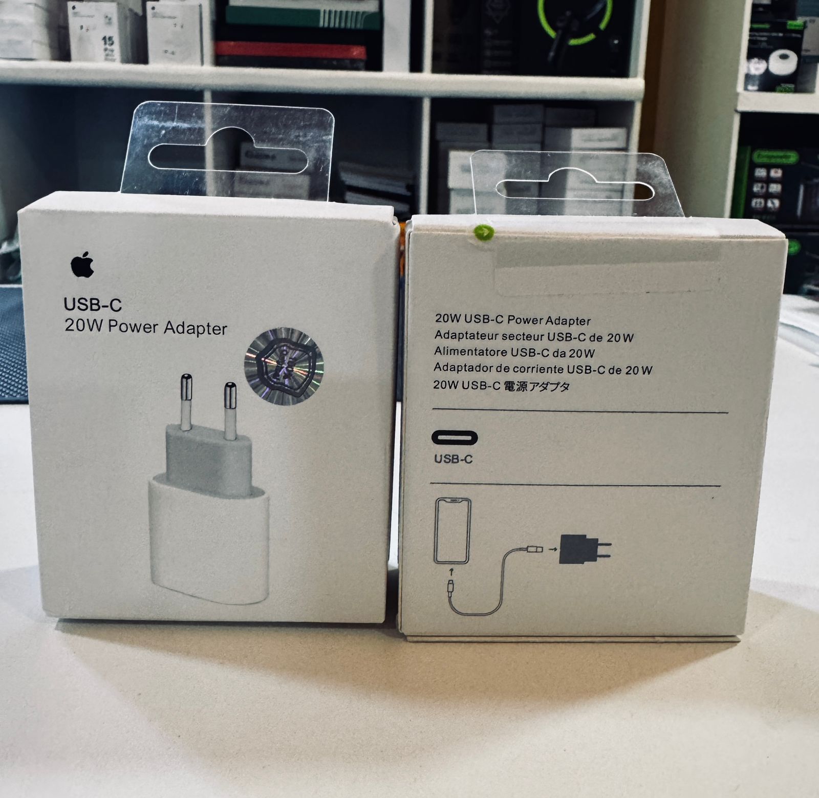 Dos cajas blancas de adaptadores de corriente Apple USB-C de 20 W con ilustraciones del cargador.
