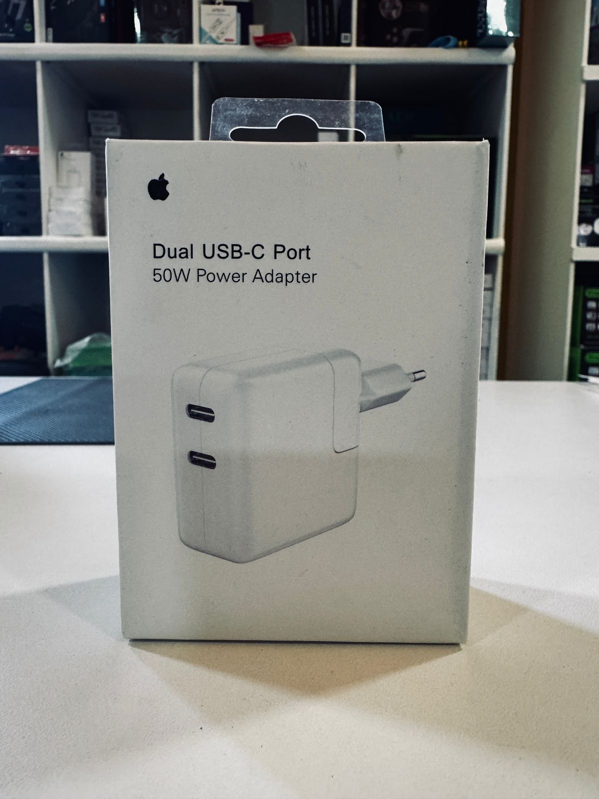 Caja del adaptador de corriente Apple de 35 W con dos puertos USB-C, blanca, sobre una mesa blanca.