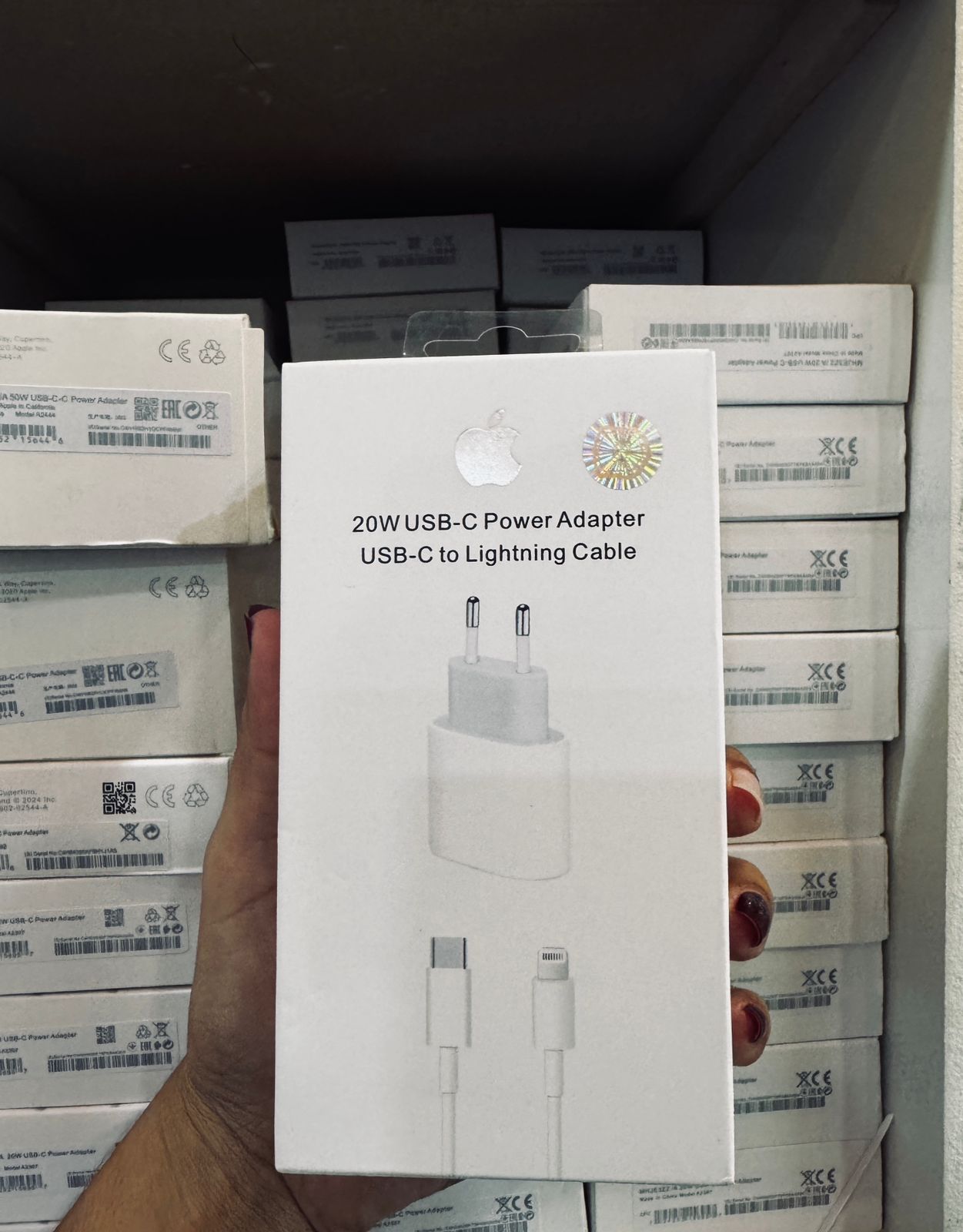 Mano sosteniendo una caja de adaptador de corriente USB-C de 20 W de Apple,