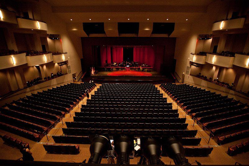 House of Worship AV soltuions. Audience in a dark auditorium; a stage with blue and purple lights, a 