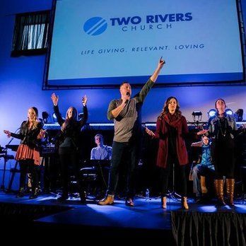 House of Worship AV solutions. Worship team on stage at Two Rivers Church; singing, blue backdrop, enthusiastic expressions.