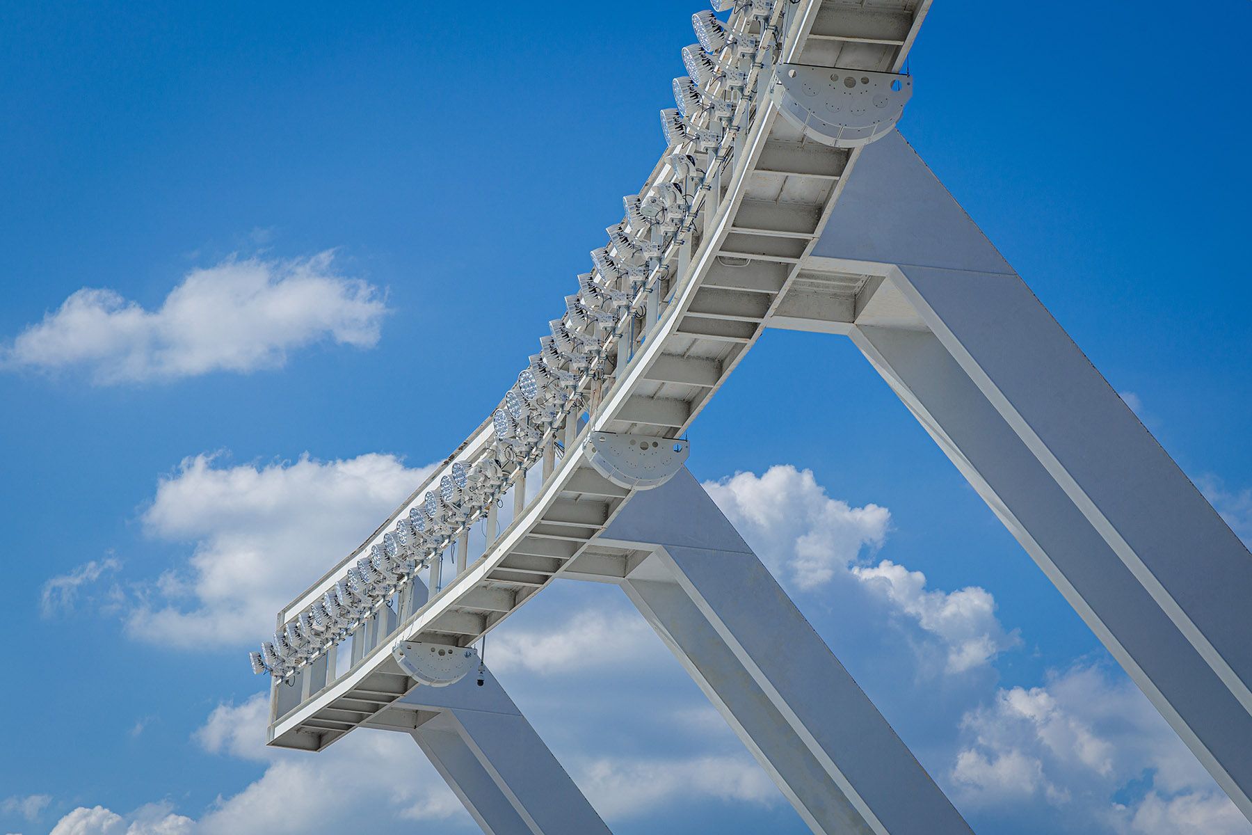 Stadium AV soltuions. White roller coaster track against a blue sky with puffy clouds.