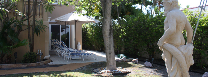 A statue of a man holding a woman in his arms in front of a house.