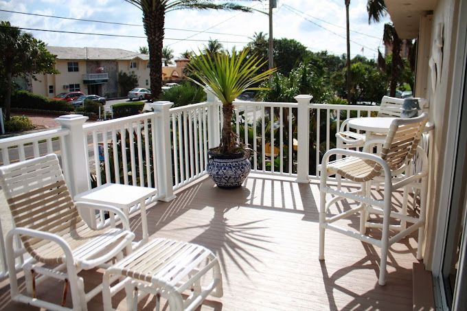 A balcony with chairs , tables and a potted plant