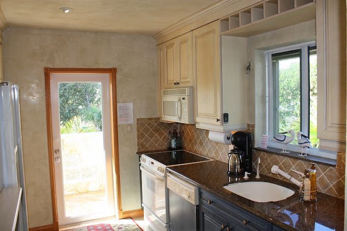A kitchen with a sink , stove , microwave and refrigerator.