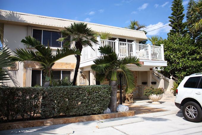 A white suv is parked in front of a house with a balcony.