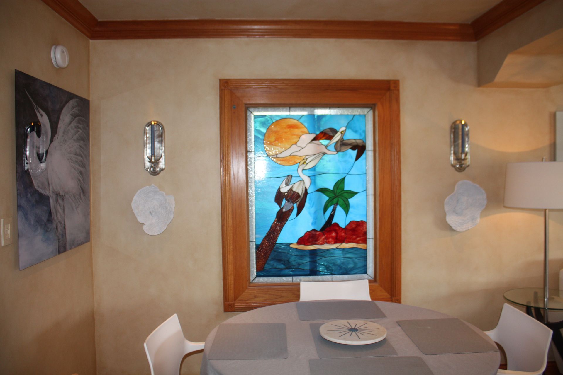 A dining room with a table and chairs and a painting on the wall