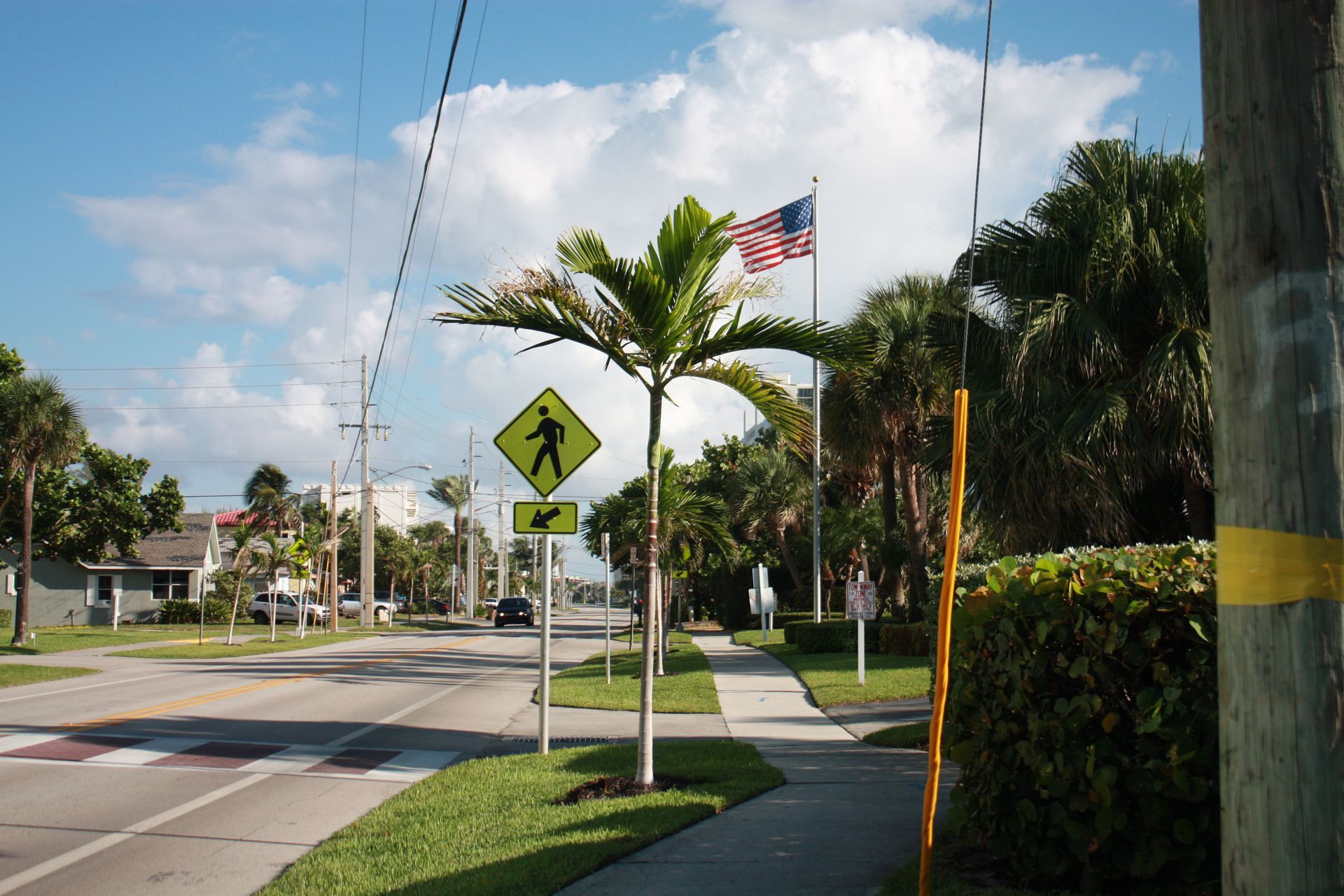 A street with a crosswalk sign and an american flag