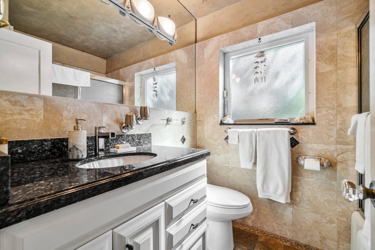 A bathroom with a sink , toilet , mirror and window.