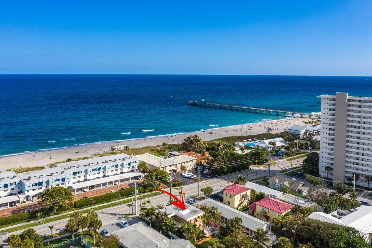 An aerial view of a beach with a red arrow pointing to a house.