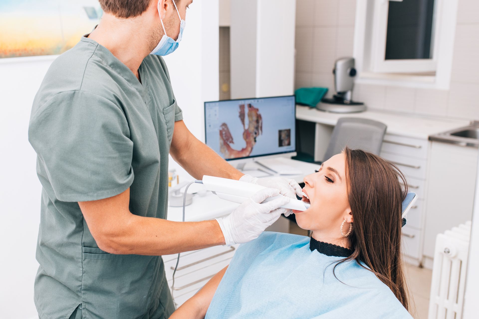 Dentist examining a woman's teeth with a scanner in a dental office.
