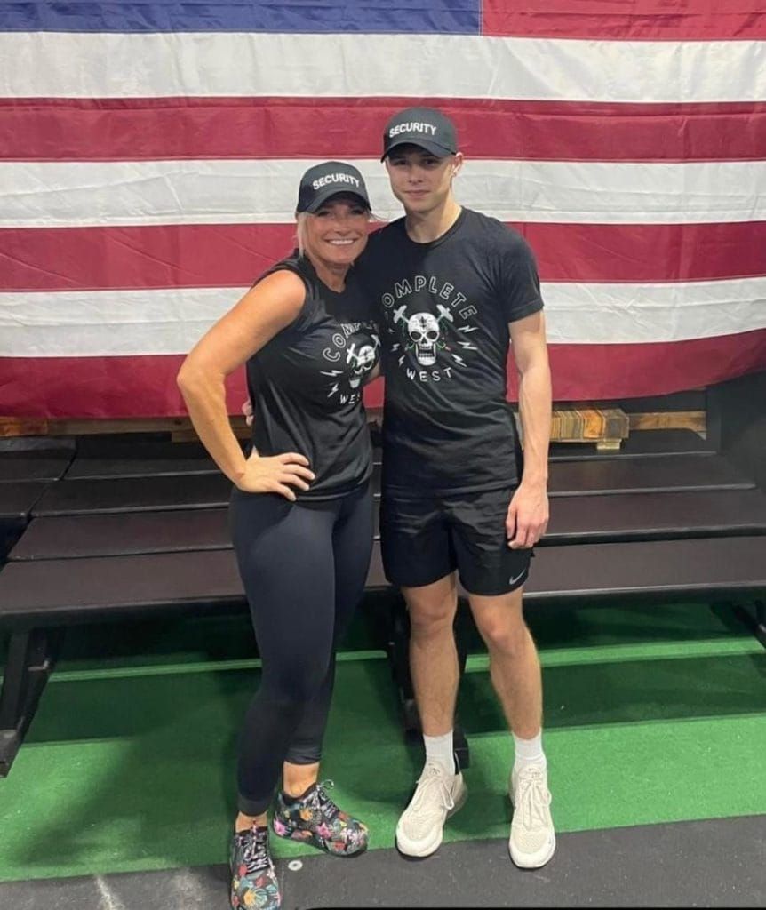 A man and a woman are posing for a picture in front of an american flag.