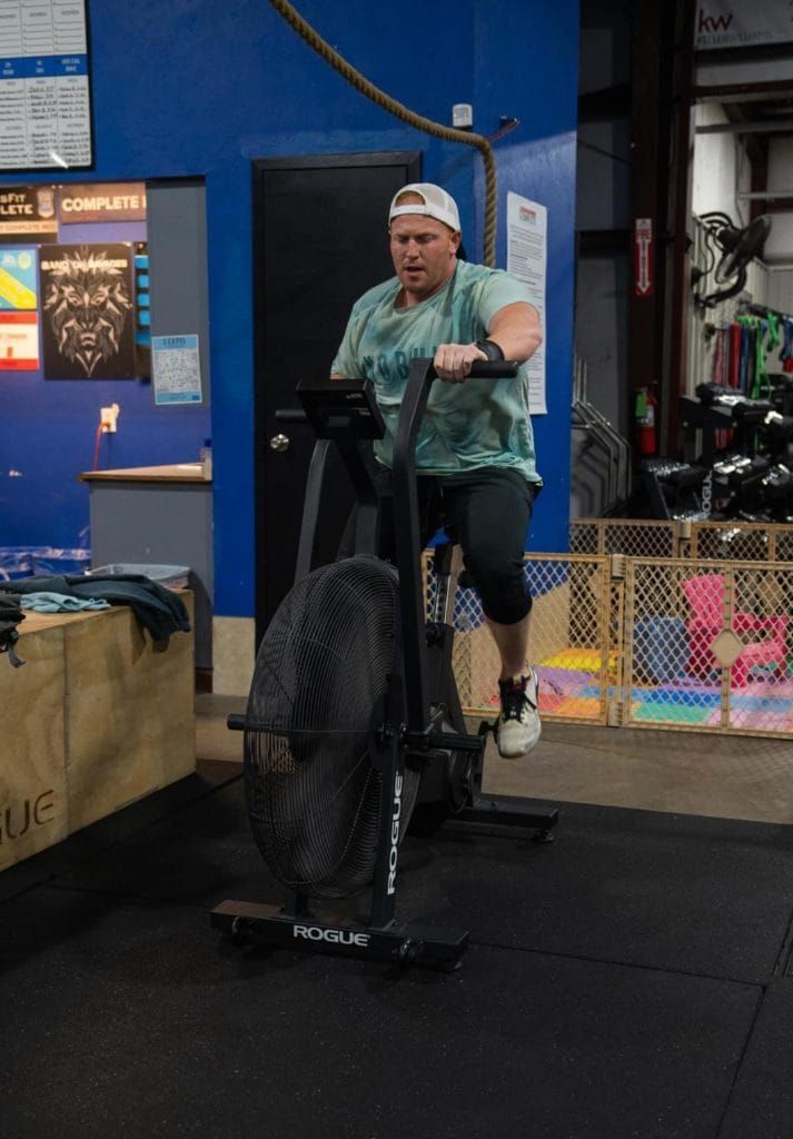A man is riding an exercise bike in a gym.