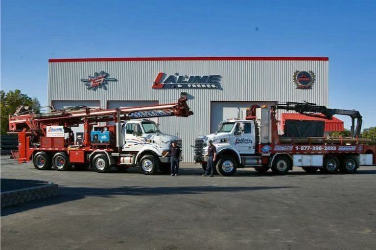 Deux camions de service rouges et blancs stationnés devant un bâtiment portant le logo « LIME ».
