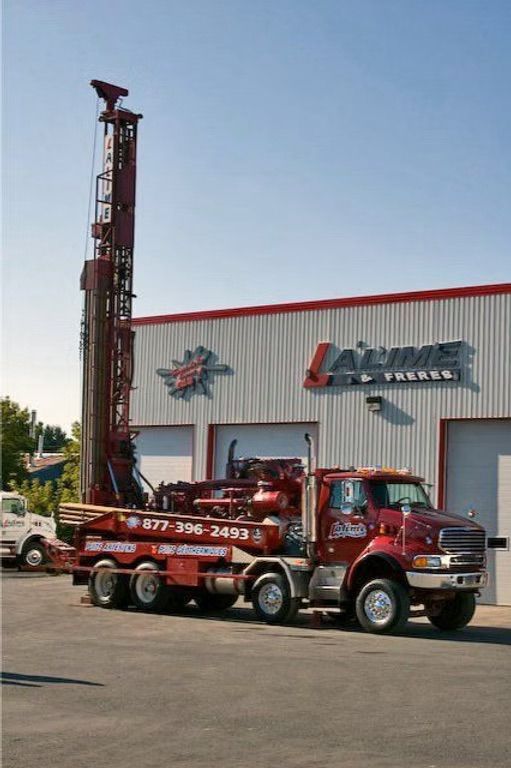 Un camion de forage rouge est stationné devant un bâtiment portant le nom de la société « LaLime ».