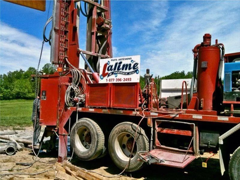 Une foreuse de puits rouge avec l'inscription « Lallme » par une journée ensoleillée.