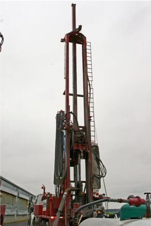 Une grande plateforme de forage rouge se détachant sur un ciel nuageux.