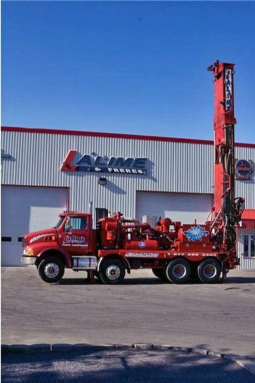 Camion de forage rouge devant un bâtiment portant le nom de la société « ALIME ».
