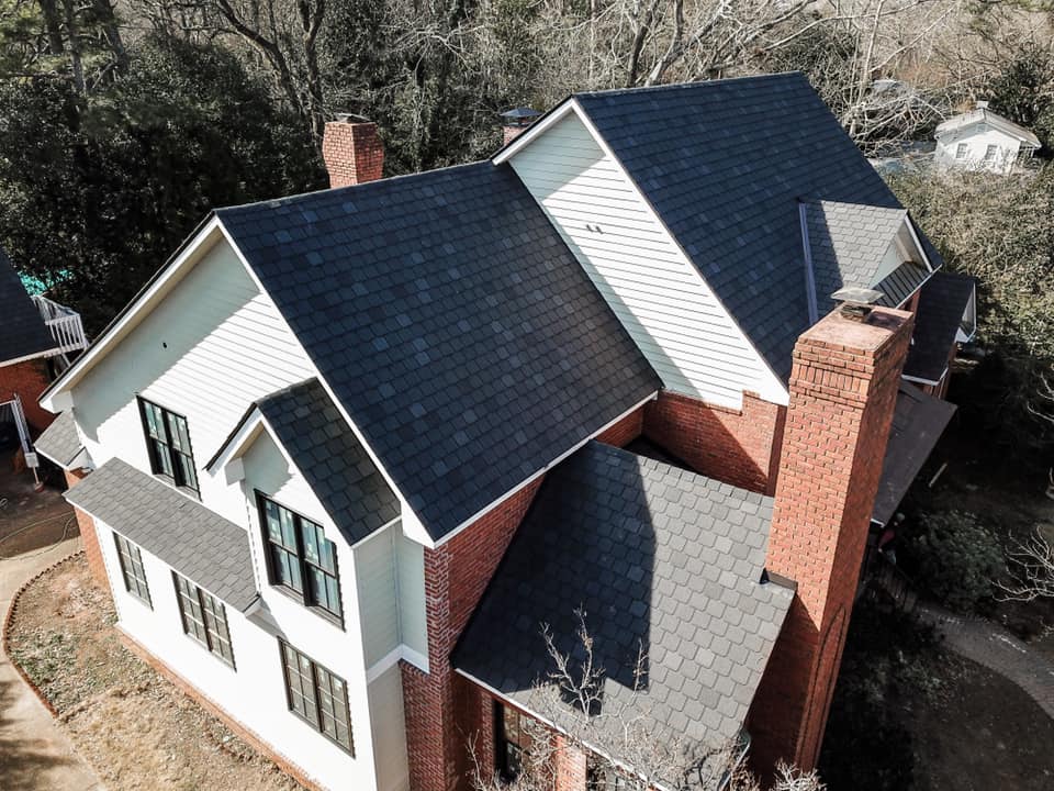 white house with red bricks and dark roof that had repairs done by Total Roof Solutions in Georgia