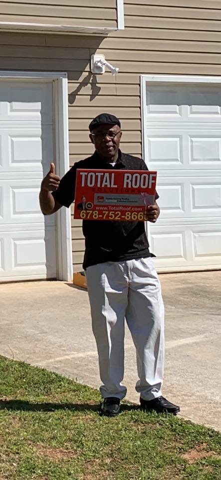 male in black polo shirt in front of white garage door Total Roof Solutions