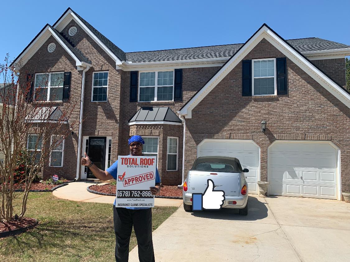 man standing in front of Total Roof Solutions repaired home