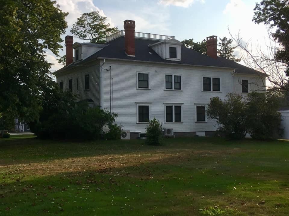White home with chimneys and dark roof in Atlanta, GA repaired by Total Roof Solutions