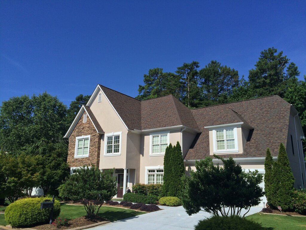 Tan home and green yard worked on by Total Roof Solutions