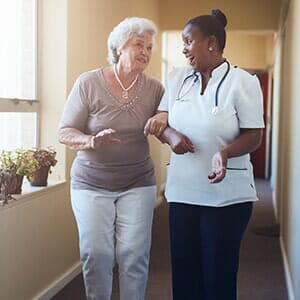 Happy healthcare worker walking and talking with senior woman - medical home in Elmhurst, NY