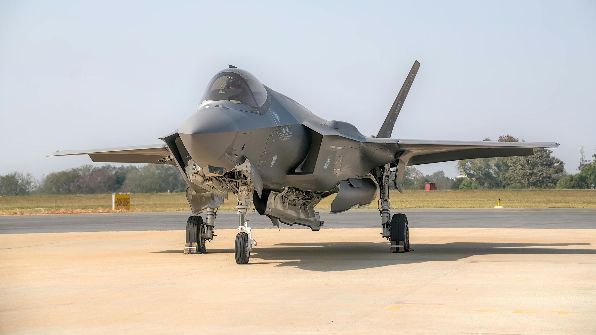 A jet airplane with landing gear down, parked in the snow, viewed from the front.