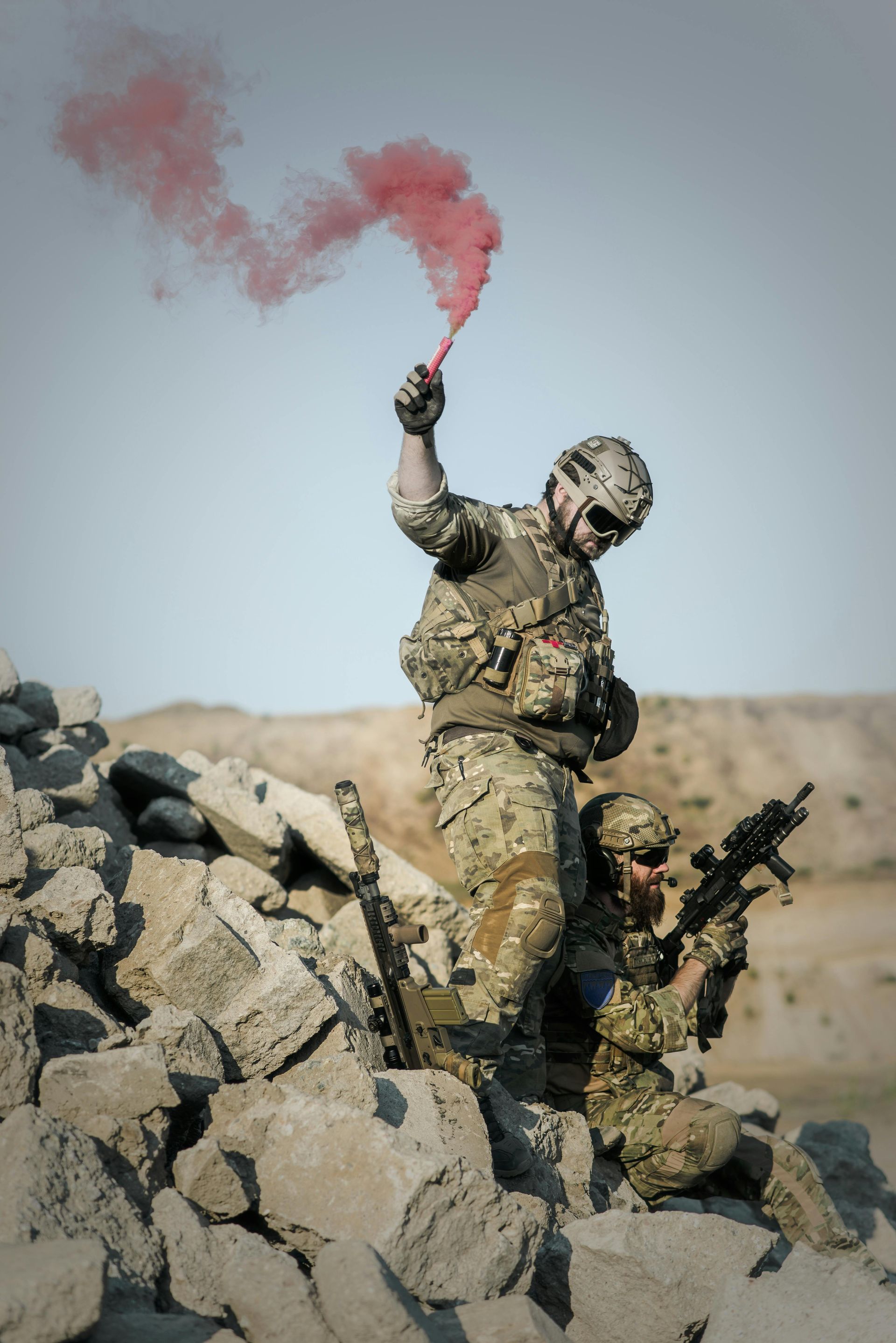 Soldier in camouflage uniform holding a rifle, looking up at cloudy sky.