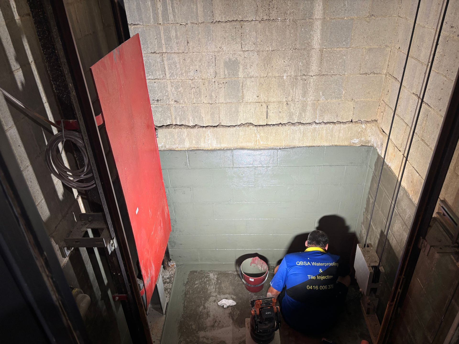 Person Applying Blue Waterproofing Sealant to a Concrete Wall — QBSA Waterproofing & Tile Injection in Portsmith, QLD