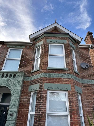 A red brick house with white windows and a blue sky in the background.