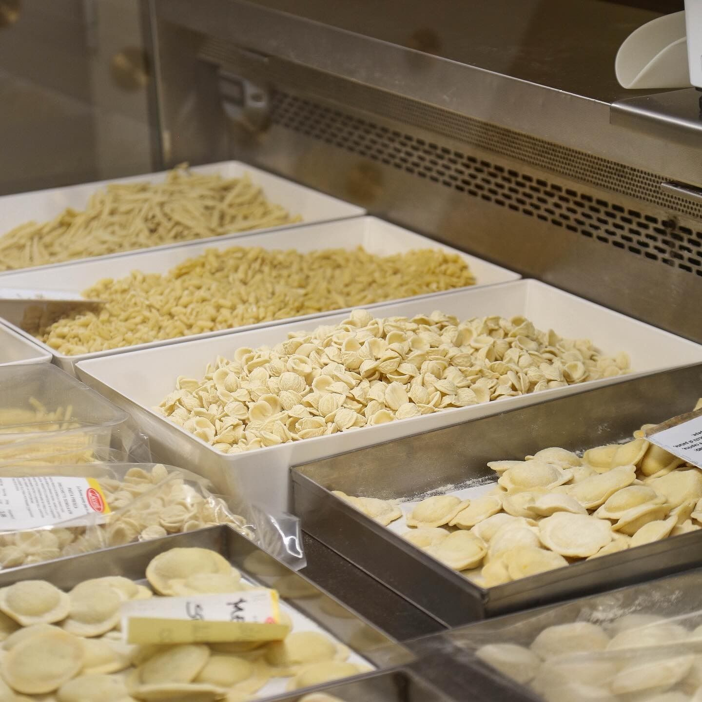 Vetrina espositiva con vari formati di pasta in un ambiente di mercato.