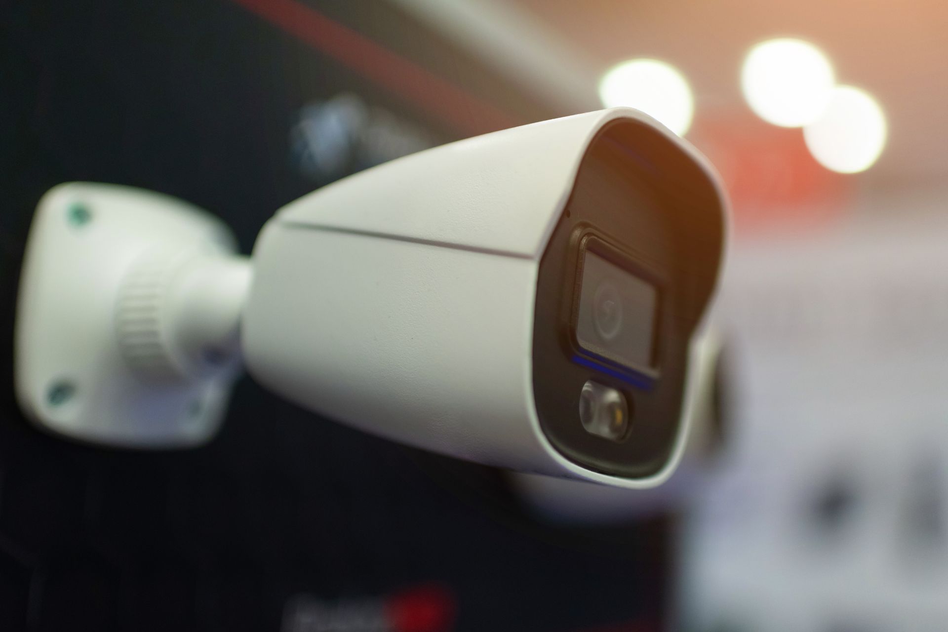 A security monitoring station with a desk and computer monitors displaying multiple live video feeds in a dim office.