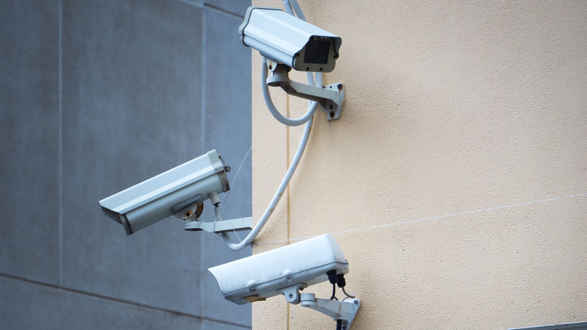 A security monitoring station with a desk and computer monitors displaying multiple live video feeds in a dim office.