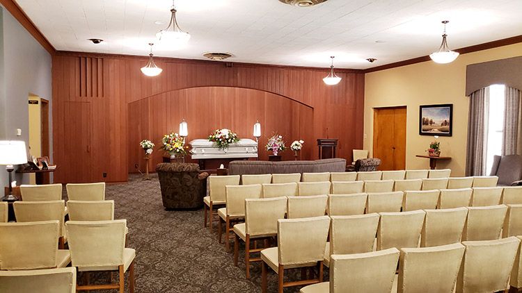 A funeral home with rows of chairs and a coffin in the background.