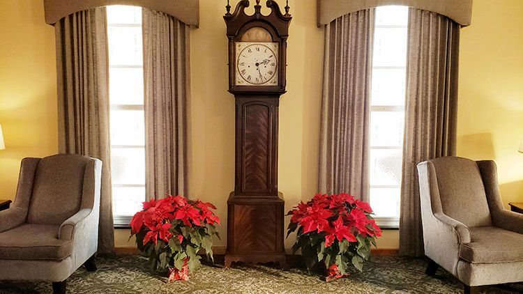 A living room with a grandfather clock and two chairs