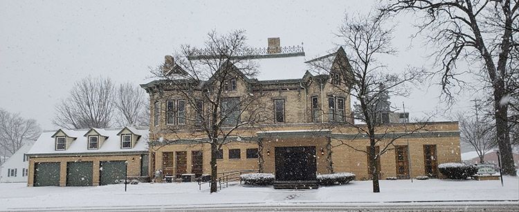 A large house with a lot of windows is covered in snow