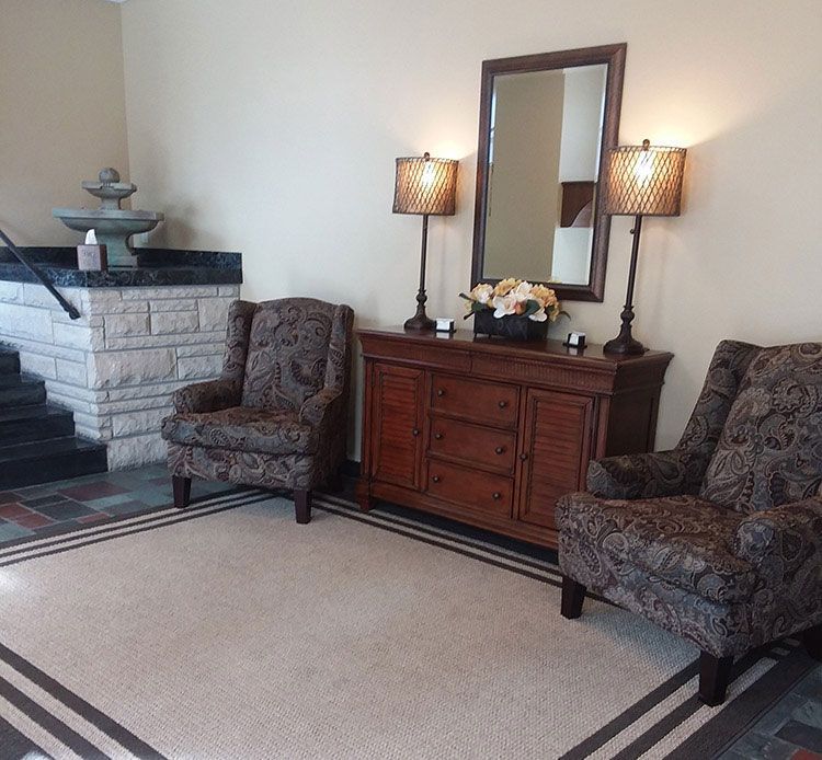 A living room with two chairs a dresser and a mirror