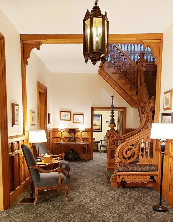 A hallway with chairs lamps and a staircase in the background