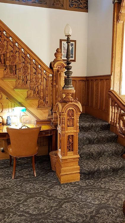 A wooden staircase with a desk and chair underneath it.