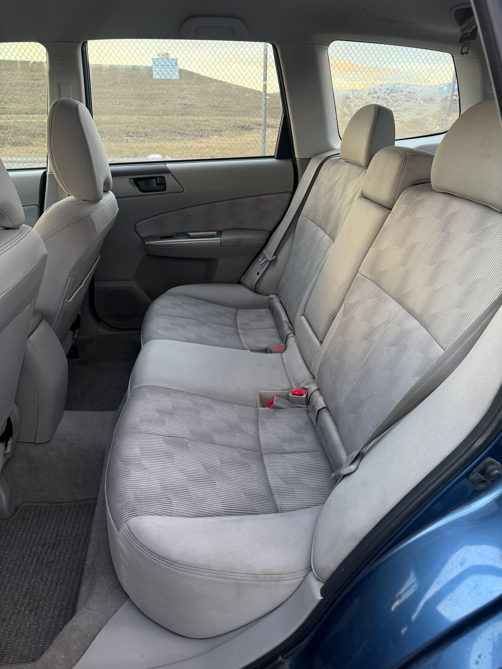 Blue car interior showing rear seats with patterned upholstery.