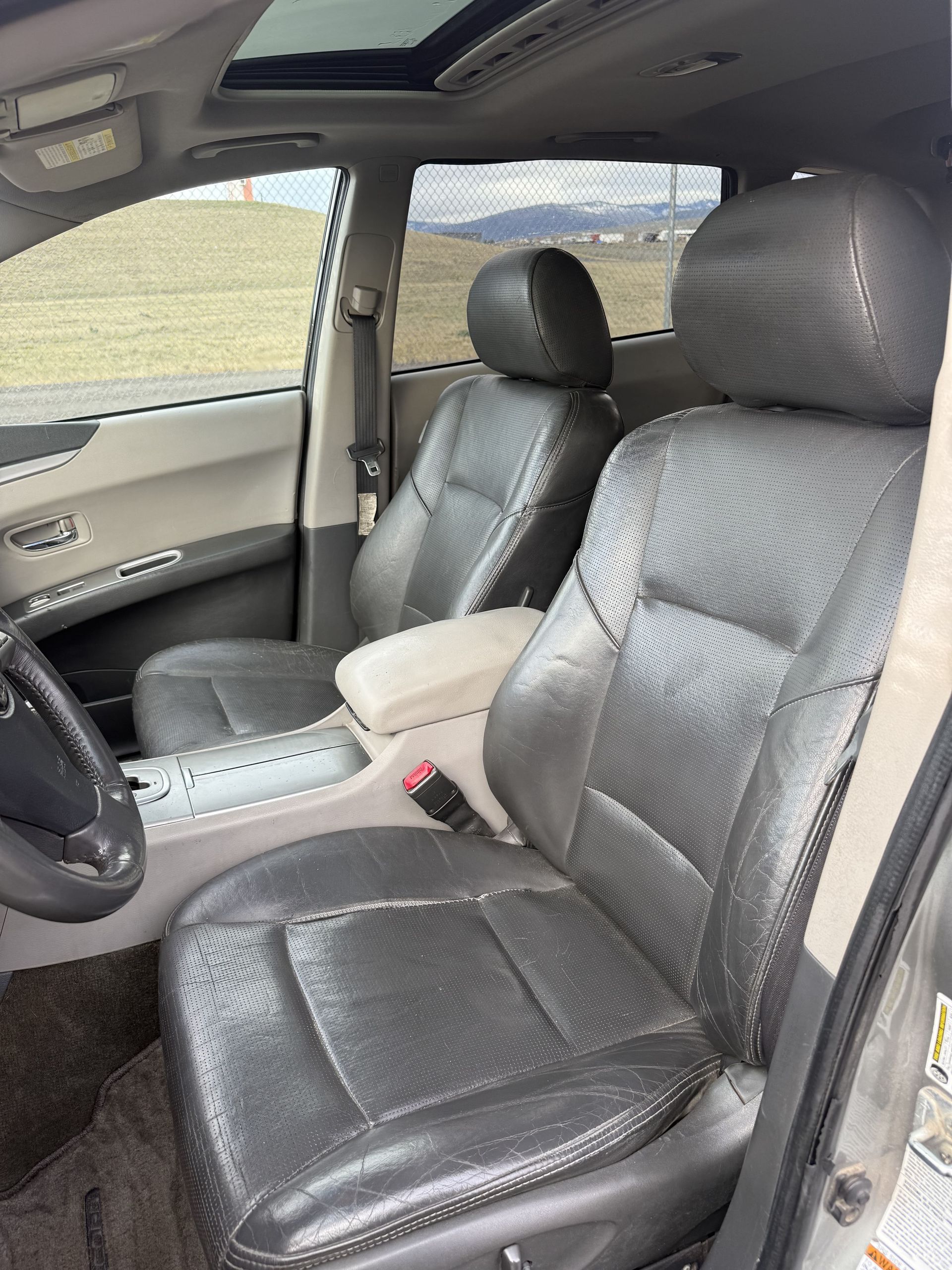 Interior view of a gray car with black leather seats, a sunroof, and a light-colored armrest.