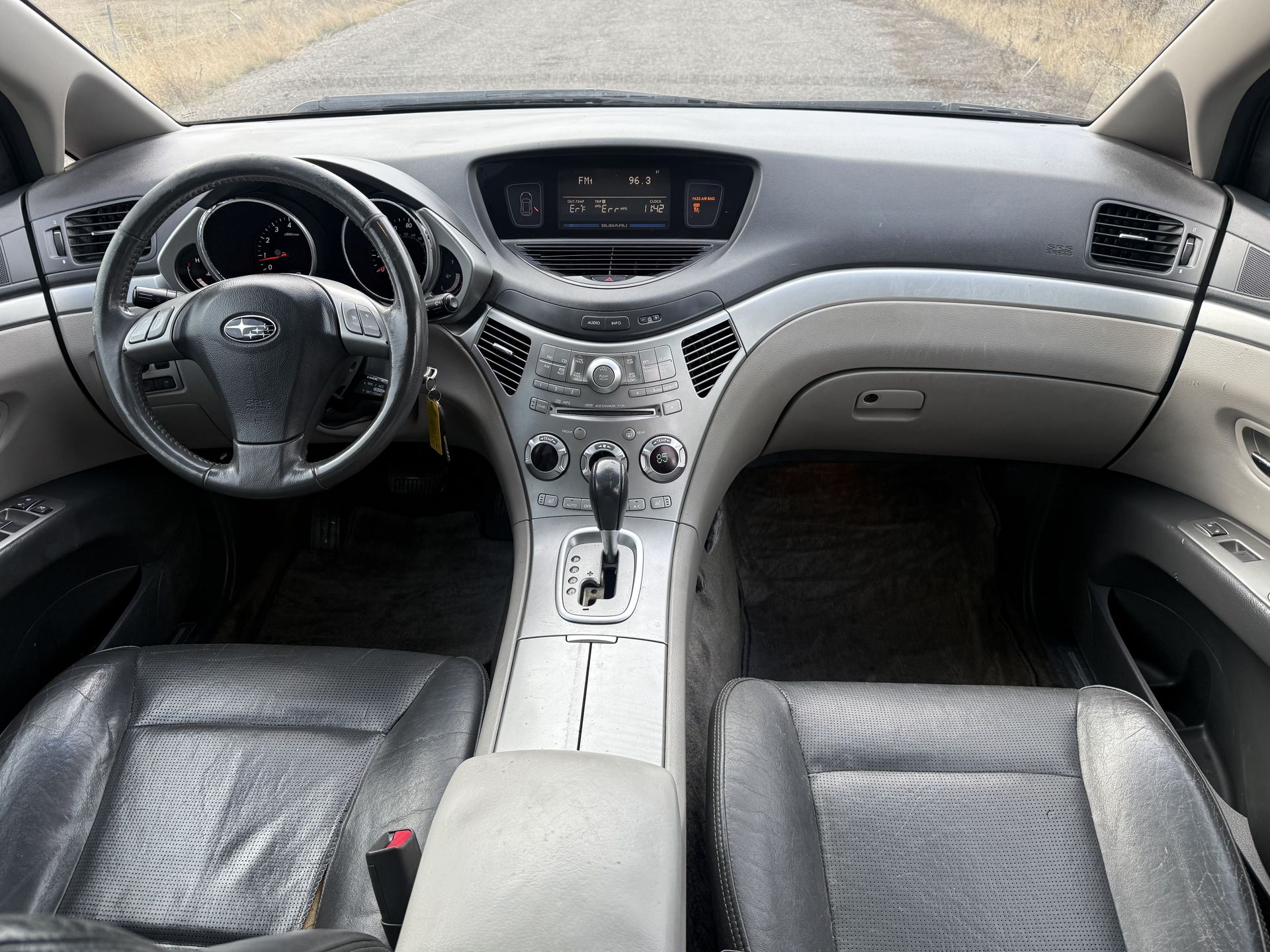 Gray and silver car interior with leather seats, dashboard, steering wheel, and gearshift.