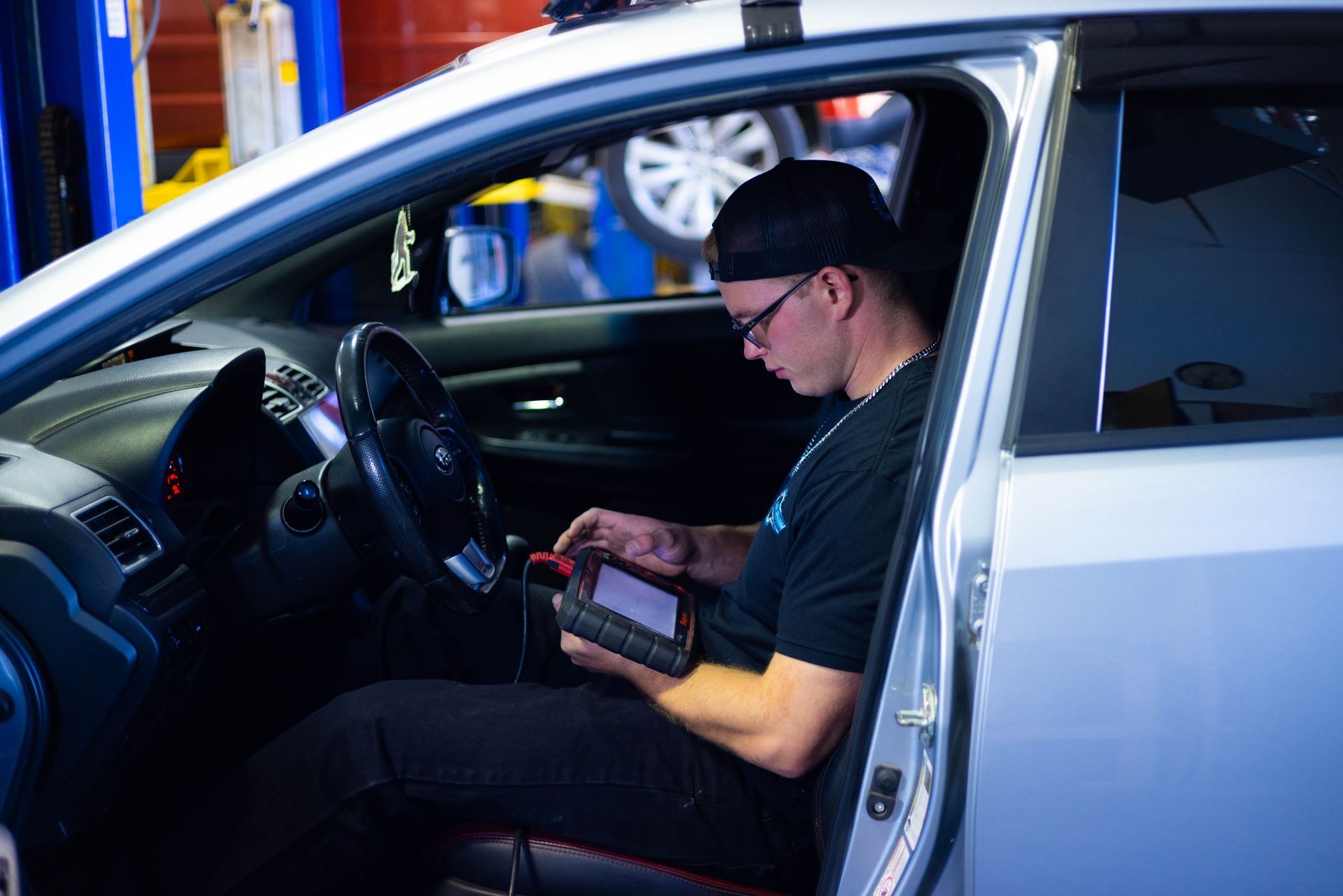 A man is sitting in a car using a tablet.