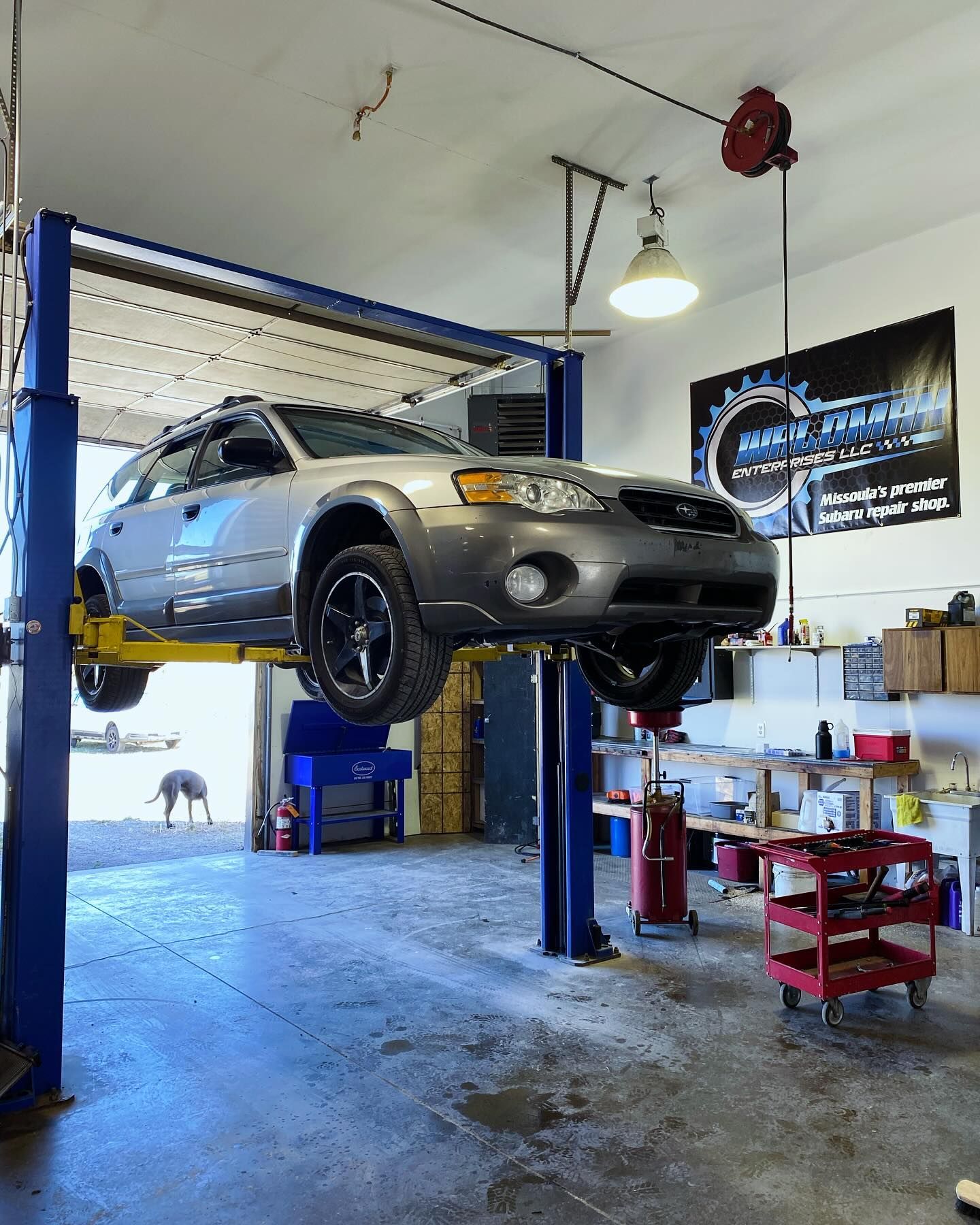 A car is sitting on a lift in a garage.