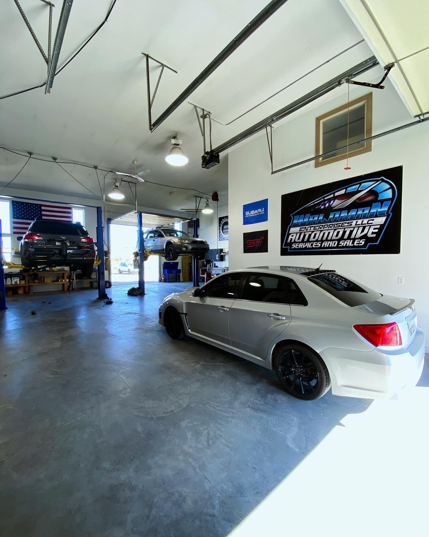 A silver car is parked in a garage with a sign on the wall.