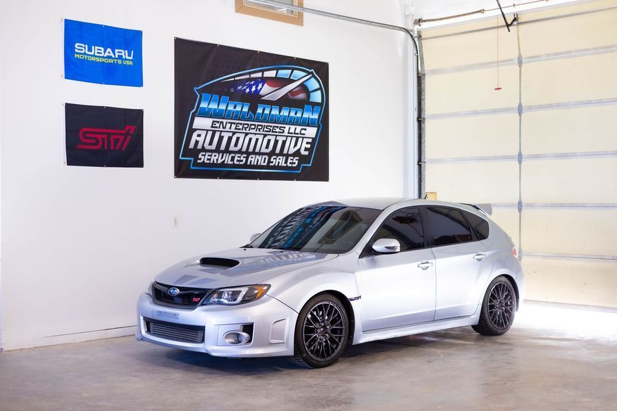 A silver subaru wrx sti is parked in a garage.