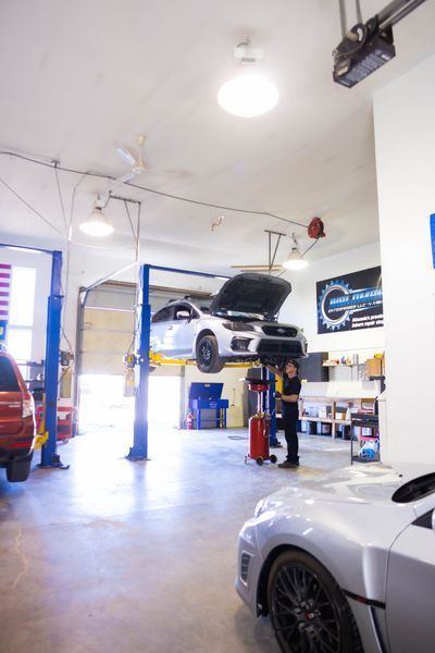 A car is sitting on a lift in a garage.