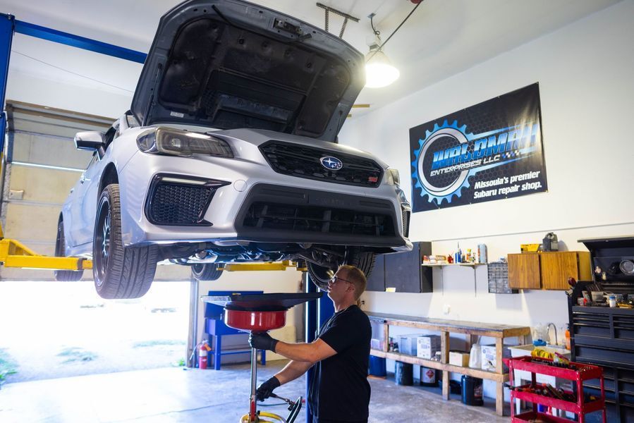 A man is working on a car on a lift in a garage.